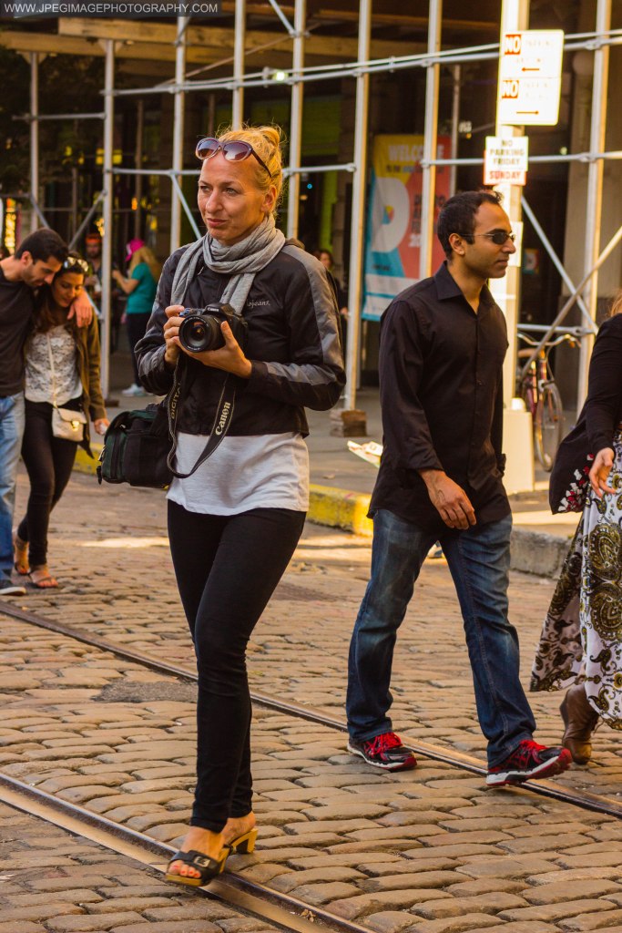 Woman walking around taking photos of the DUMBO Arts Festival located in DUMBO Brooklyn, Sunday September 29, 2013.